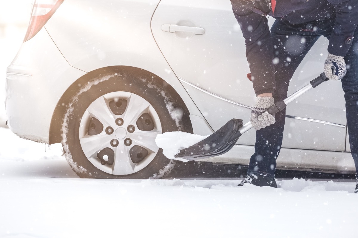 Man shoveling snow next to his car