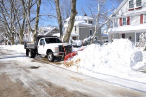 truck with snow plow removing snow from street