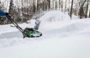 snow blower being used to remove thick layer of snow from driveway